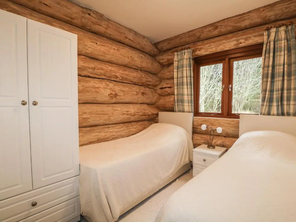 a bedroom with two beds in a log cabin at Moorhen Lodge in Inverness