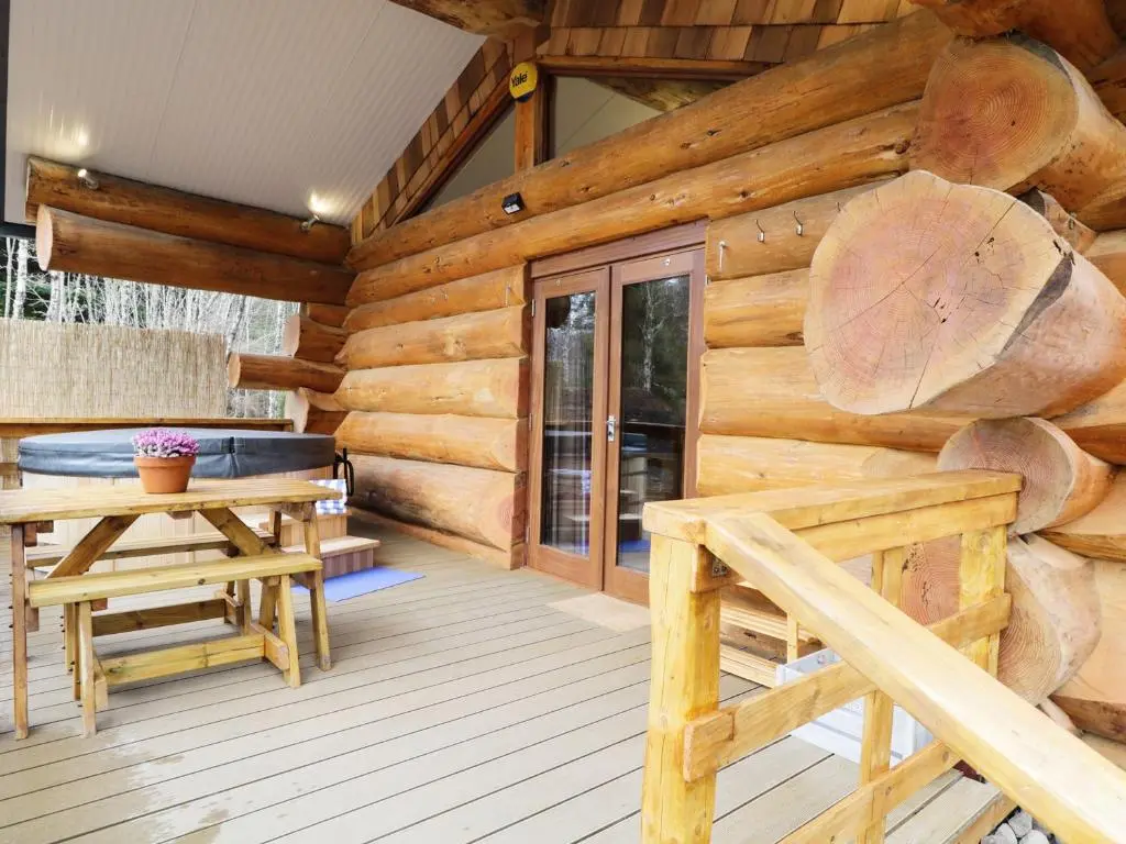 a log cabin porch with a bench and a table at Moorhen Lodge in Inverness