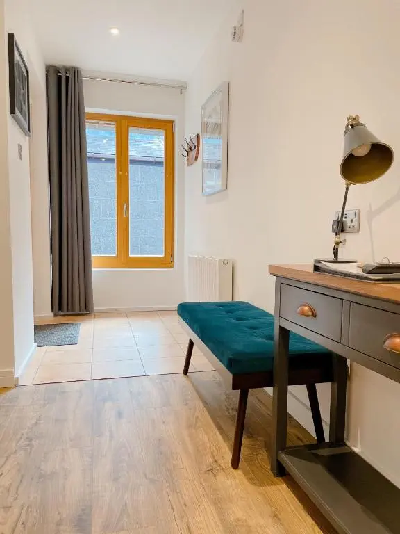 a living room with a desk and a green bench at Ravenscraig Guest House in Aviemore