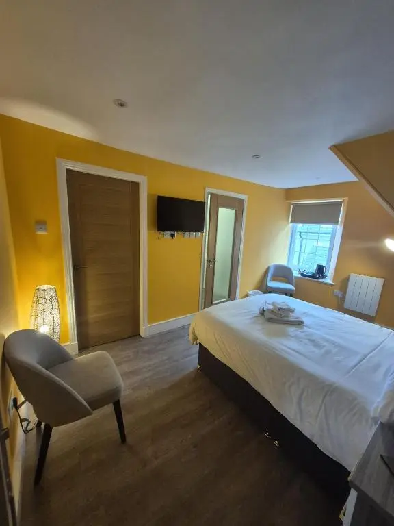a bedroom with a bed and a chair in it at Haughton Arms Hotel in Alford