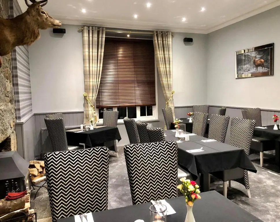 a restaurant with tables and chairs and a deer head on the wall at Haughton Arms Hotel in Alford