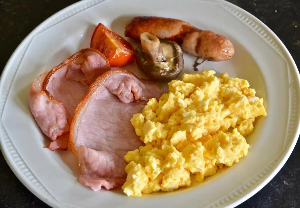 a white plate with eggs bacon sausage and mushrooms at Home Farm Bed and Breakfast in Muir of Ord