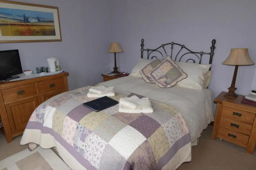 a bedroom with a bed with a book and a tv at Home Farm Bed and Breakfast in Muir of Ord