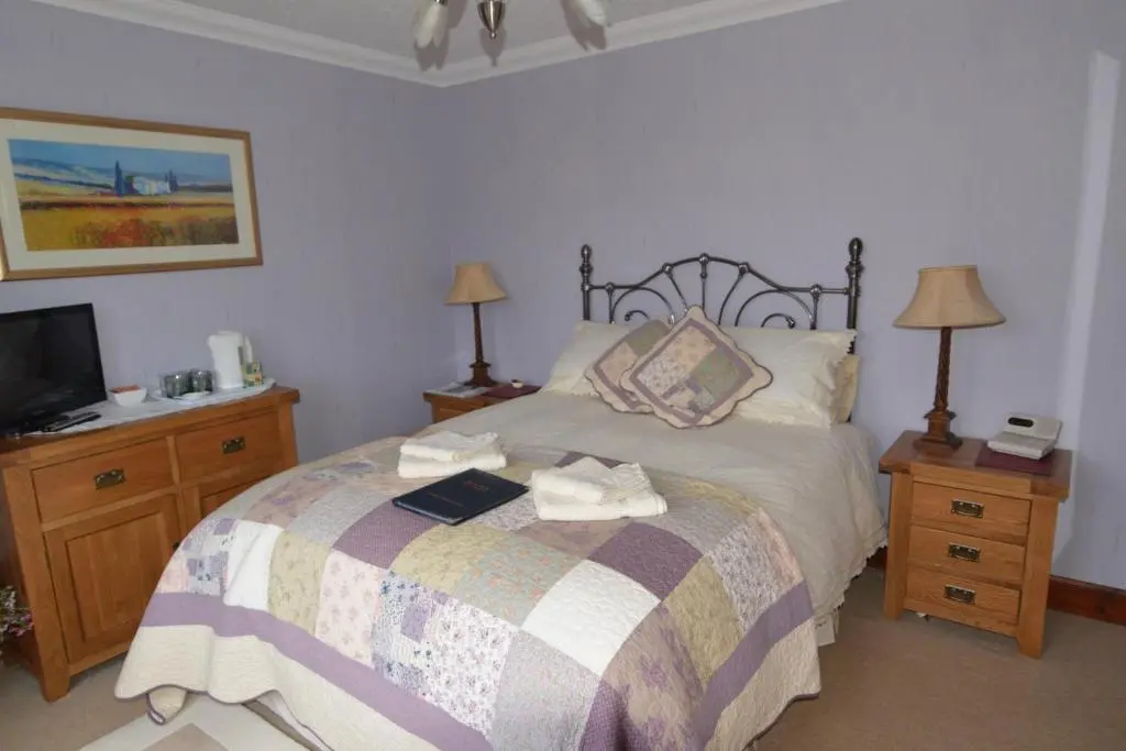 a bedroom with a bed with a book on it at Home Farm Bed and Breakfast in Muir of Ord
