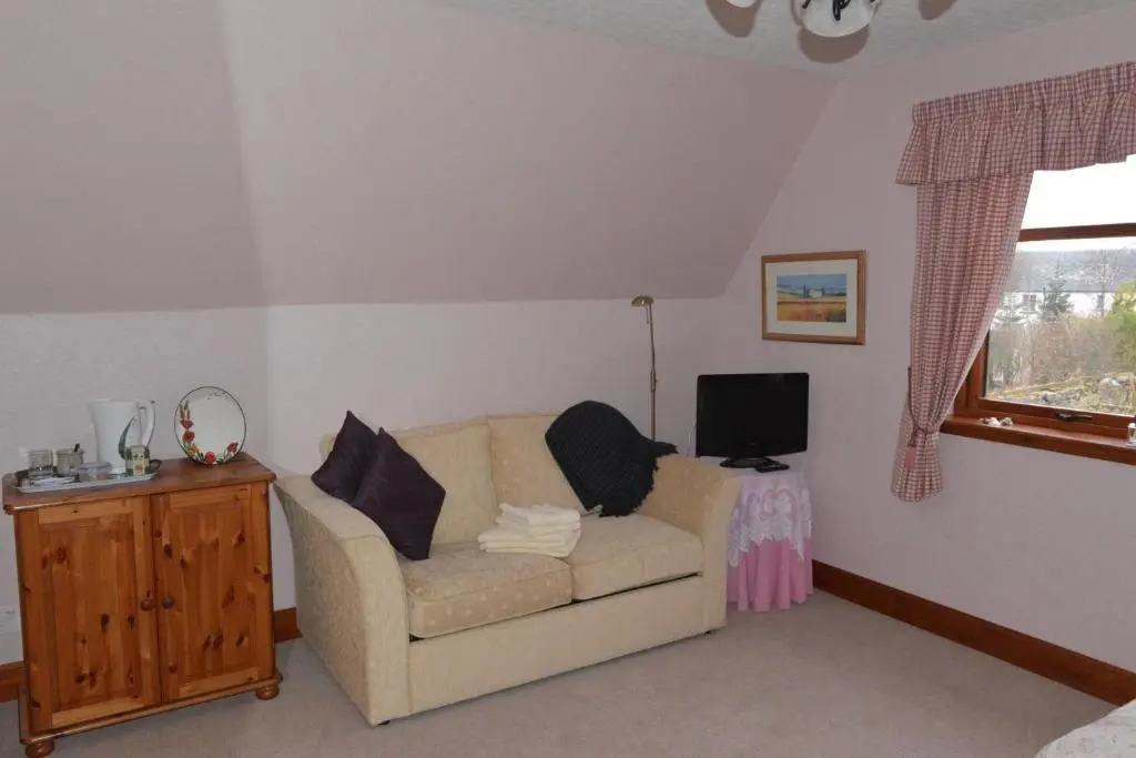 a living room with a couch and a television at Home Farm Bed and Breakfast in Muir of Ord