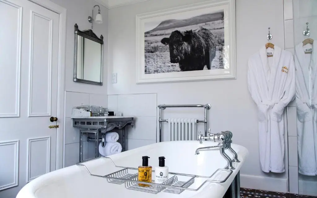 a bathroom with a white tub and a cow picture on the wall at Mount Barker in Grantown on Spey