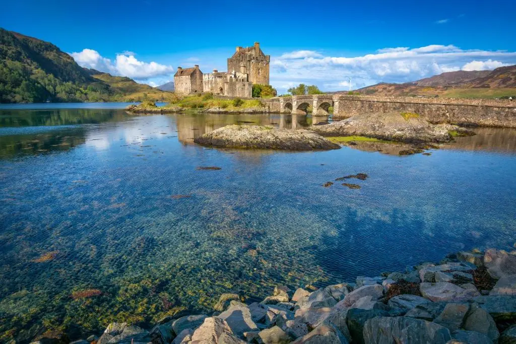 a castle on an island in a body of water at Lann Dearg Studios in Invermoriston