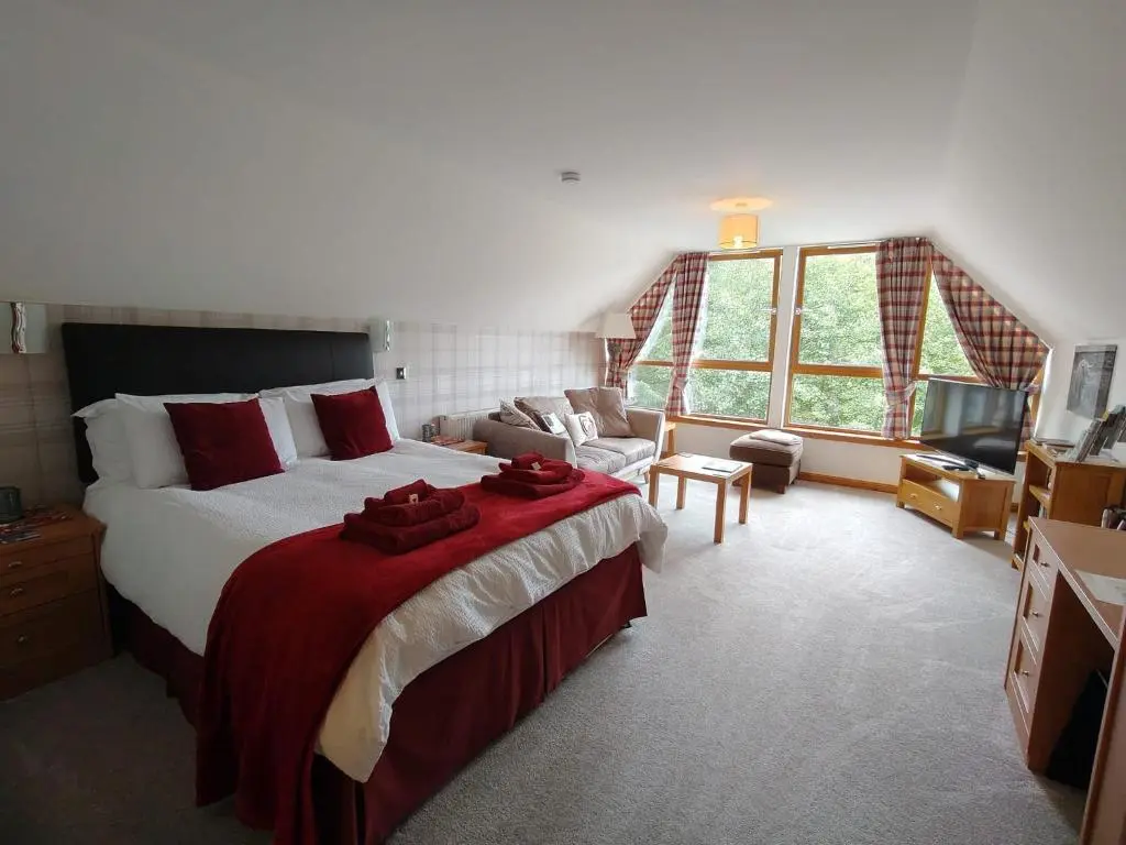 a bedroom with a large bed and a couch at Lann Dearg Studios in Invermoriston