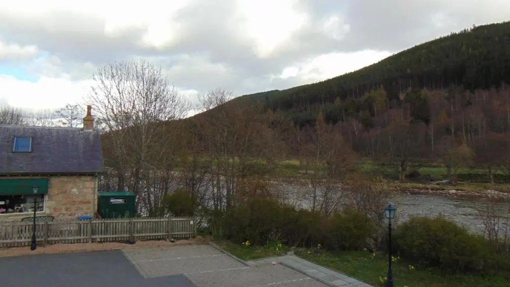 a house next to a river with a mountain at Montclaire in Ballater