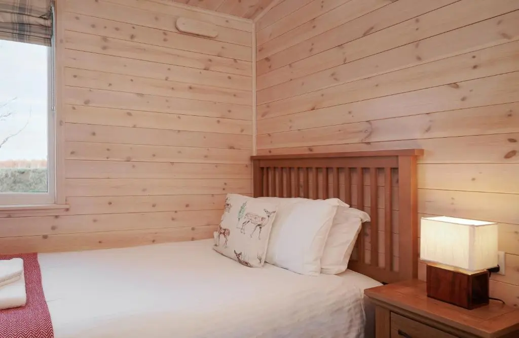 a bedroom with a bed in a wooden wall at Burgie Woodland Lodges in Forres