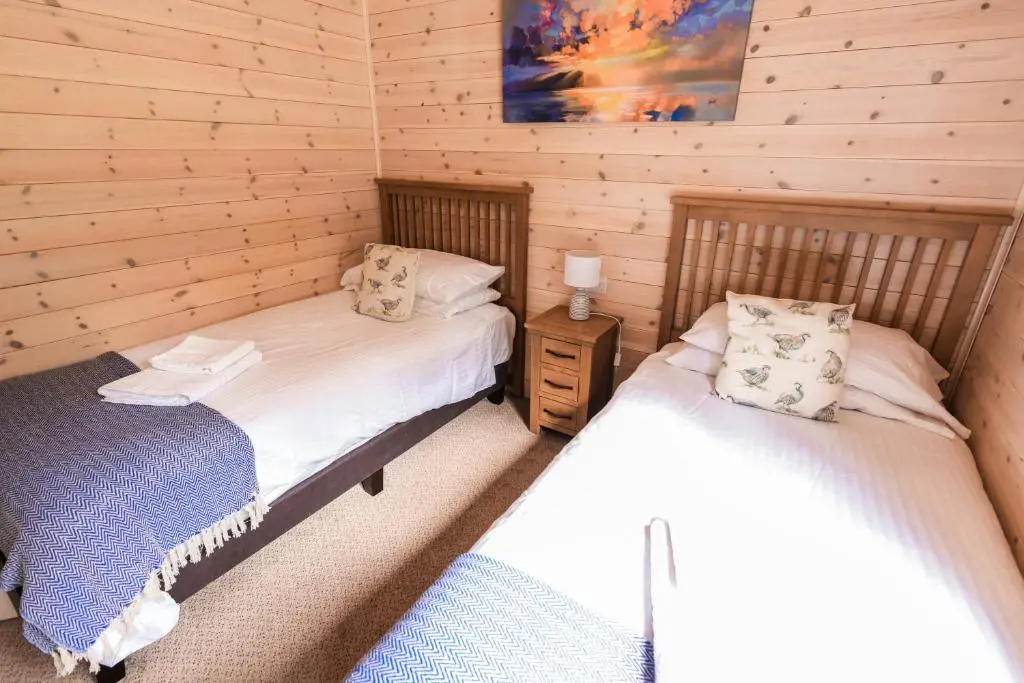 a bedroom with two beds in a log cabin at Burgie Woodland Lodges in Forres