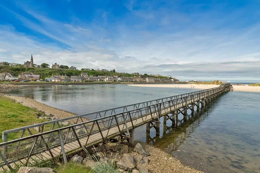 a wooden bridge over the water near a beach at 37A Commerce Street in Lossiemouth