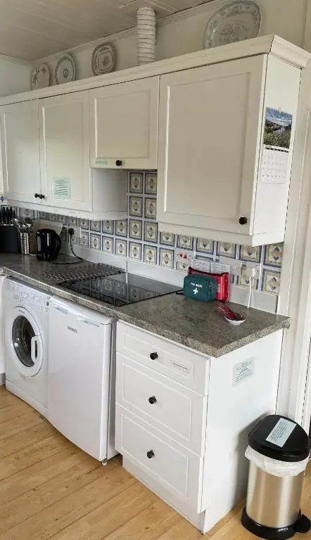 a kitchen with white cabinets and a washer and dryer at The Stroops in Helmsdale