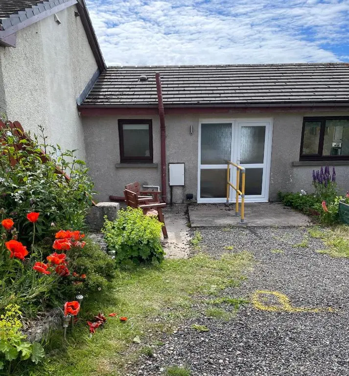 a house with red flowers in front of it at The Stroops in Helmsdale