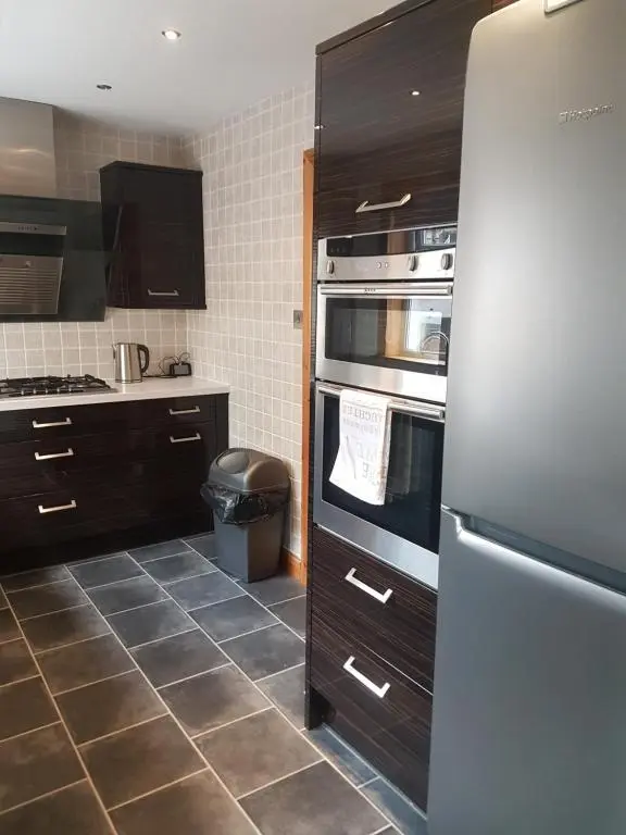 a kitchen with a stainless steel refrigerator and tile floors at Jane's Place Free Parking in Inverness