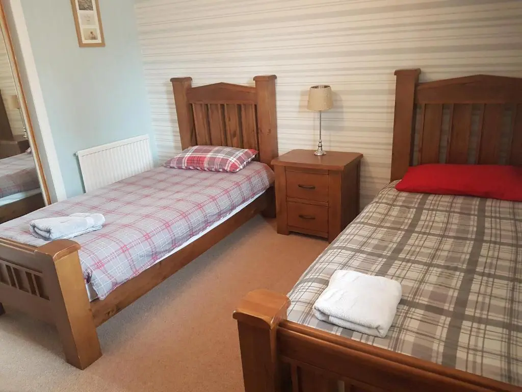 a bedroom with two twin beds and a night stand at Jane's Place Free Parking in Inverness