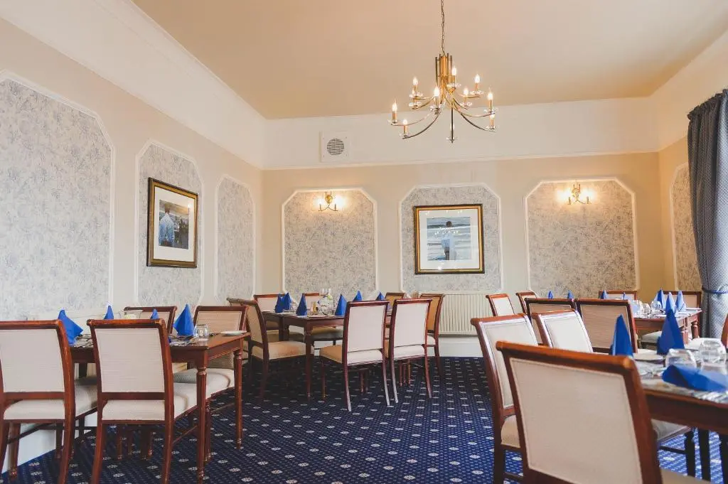 a dining room with tables and chairs and a chandelier at Sunninghill Hotel in Elgin