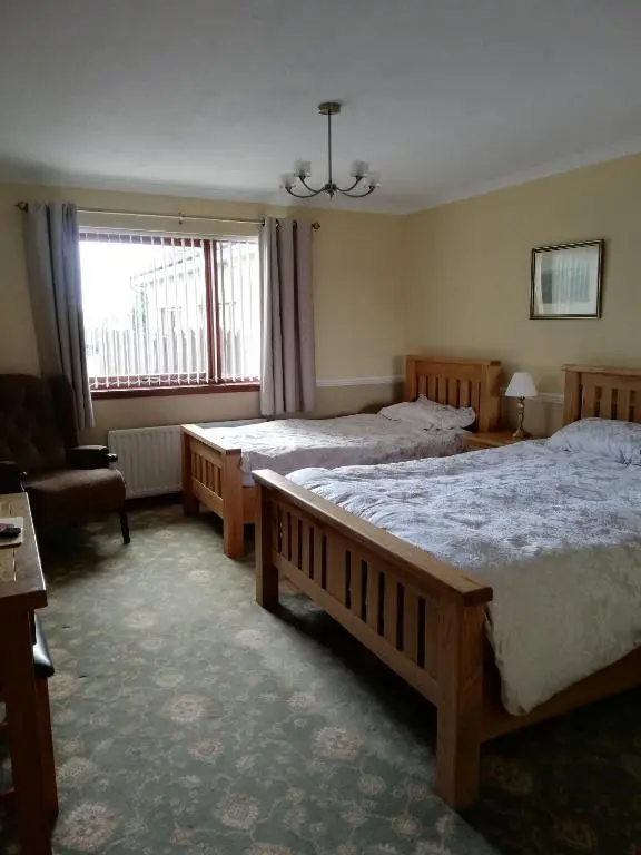 a bedroom with two beds and a chair and a window at Hillview Park in Beauly
