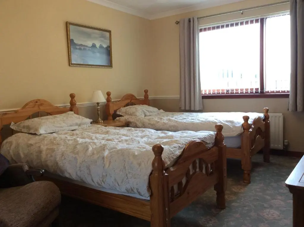 a bedroom with two beds and a window at Hillview Park in Beauly