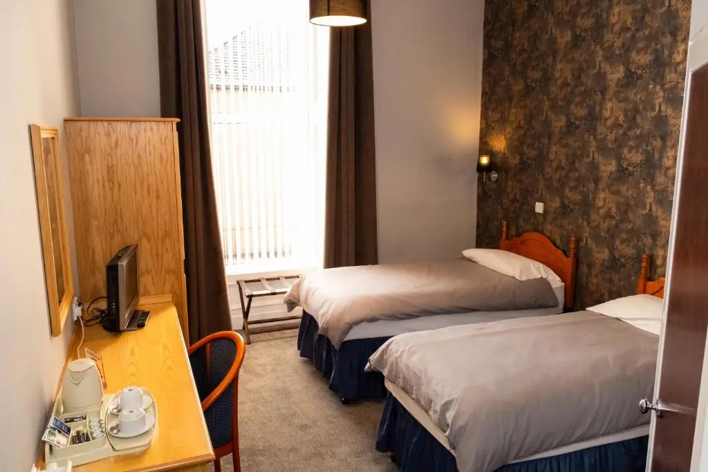 a hotel room with two beds and a desk at Station Hotel in Ellon