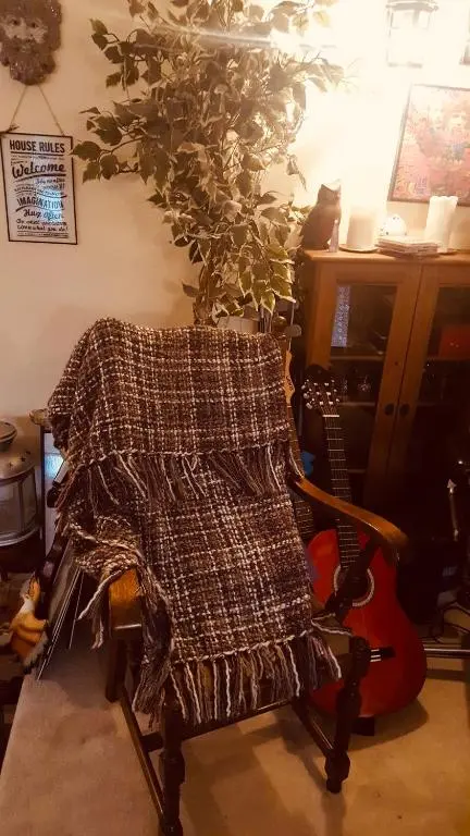 a blanket on a chair in a room with a guitar at Gordon House in Tomintoul