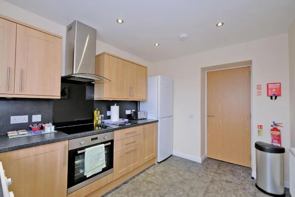 a kitchen with wooden cabinets and a white refrigerator at Caledonia Netherhills Apartment in Aberdeen