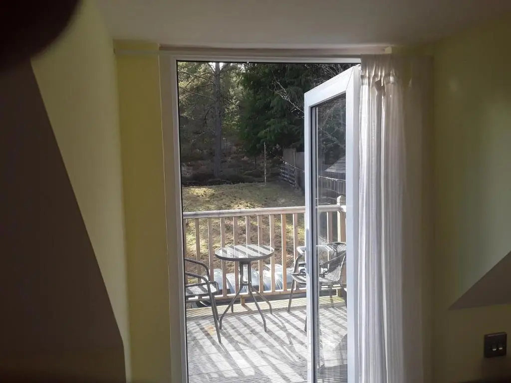 an open door to a balcony with a table and chairs at The Den , Sengera in Inverness