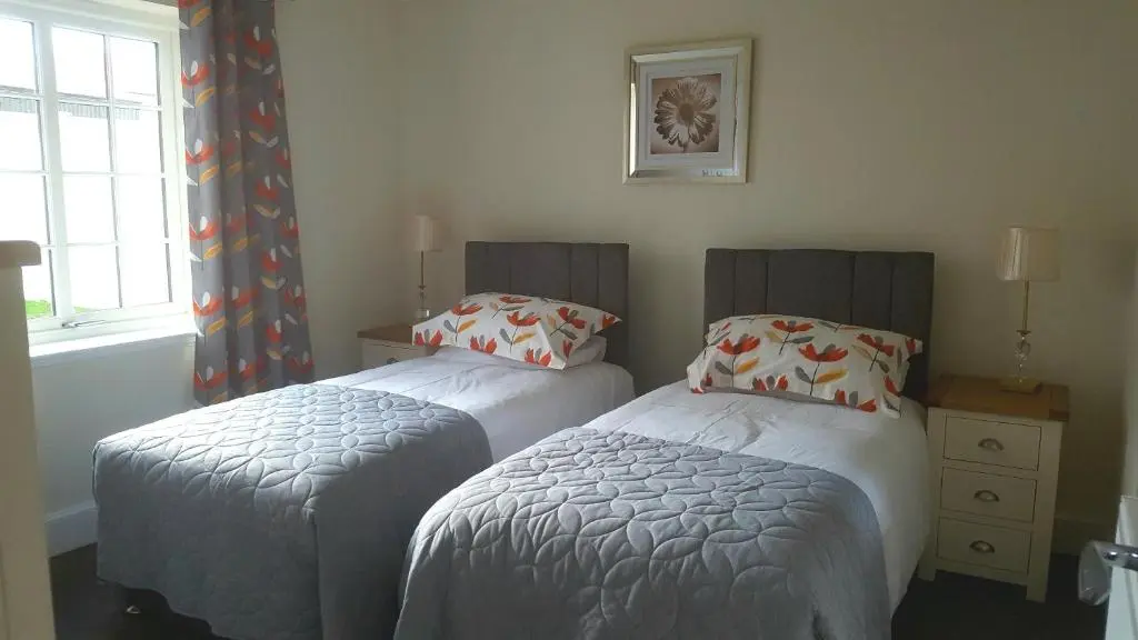 two twin beds in a room with a window at Olavat Cottage detached property with parking in Inverness