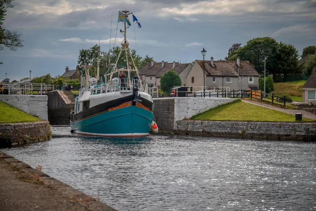 a blue boat is docked in a canal at Caledonian Canal Studio in Inverness