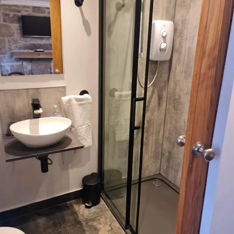 a bathroom with a sink and a glass shower at Ness City Cottage in Inverness