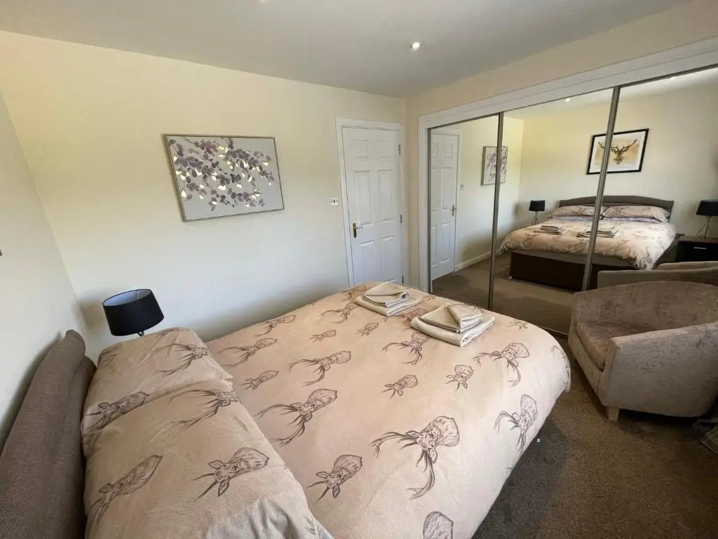 a bedroom with a bed and a chair and a mirror at Holm from Home in Inverness