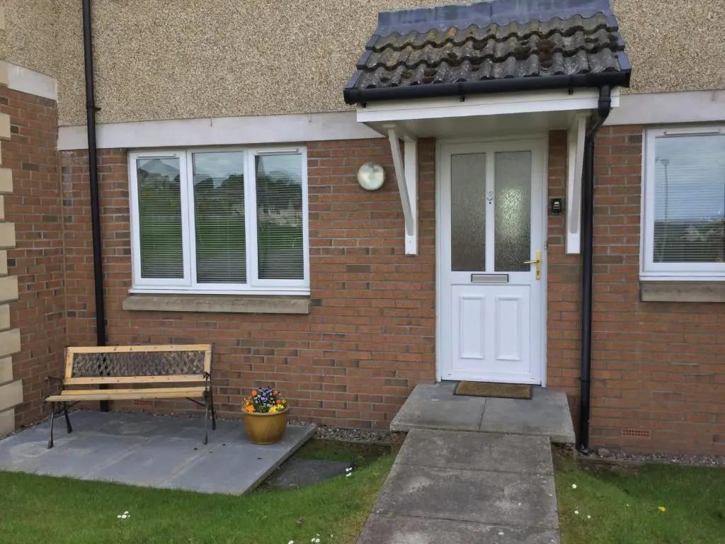 a brick house with a white door and a bench at Morning Field Apartment Free Parking in Inverness