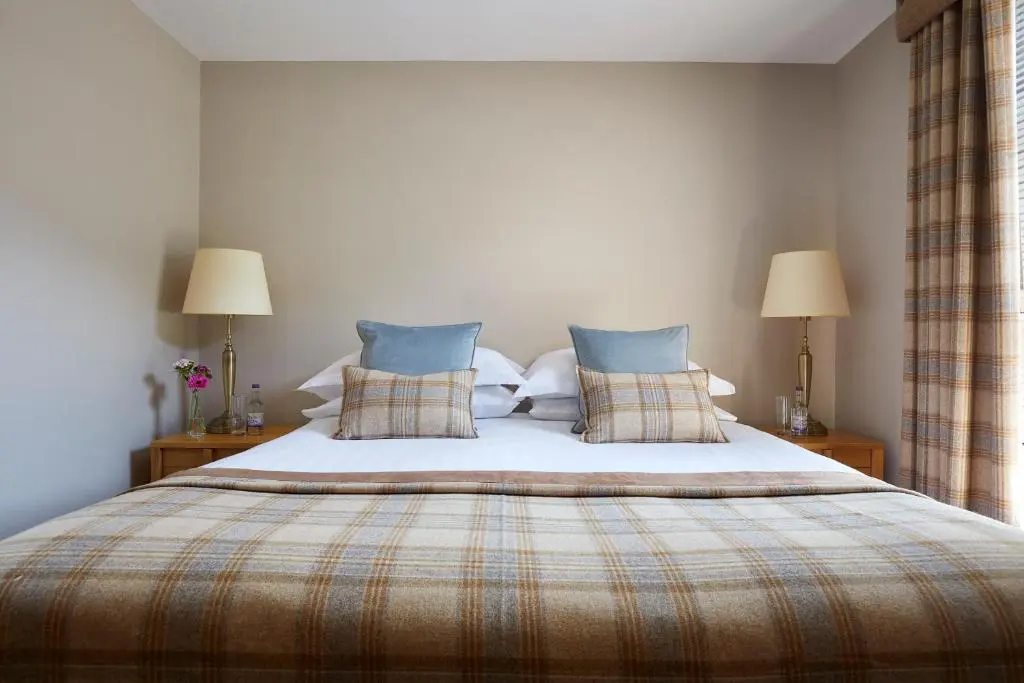 a bedroom with a large bed with two lamps at Macdonald Woodland Lodges at Macdonald Aviemore Resort in Aviemore