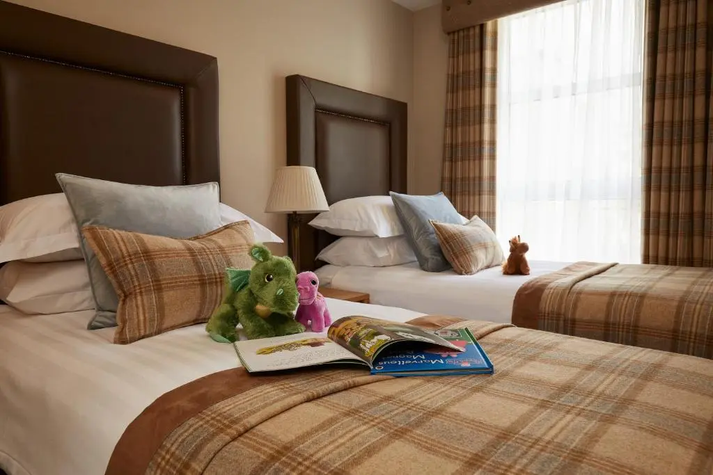 a hotel room with two beds with stuffed animals and a book at Macdonald Woodland Lodges at Macdonald Aviemore Resort in Aviemore