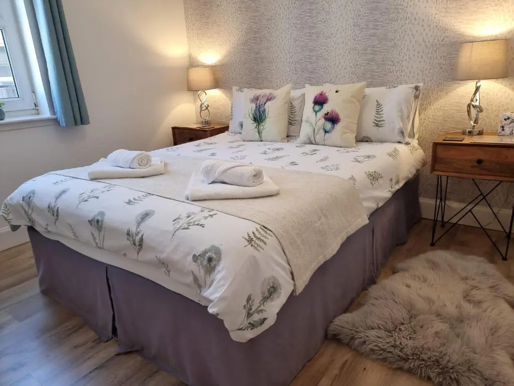 a bedroom with a large bed with towels on it at Heart of Inverness-city apartment in Inverness