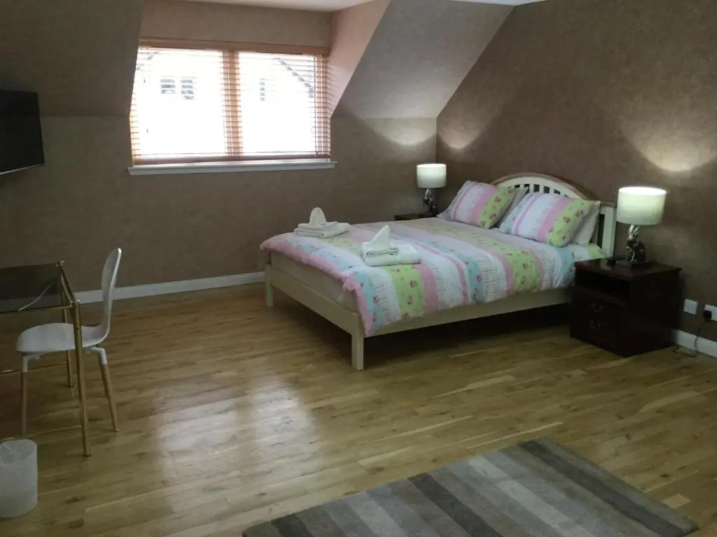 a bedroom with a bed and a table and a window at West Heather House Free Parking in Inverness