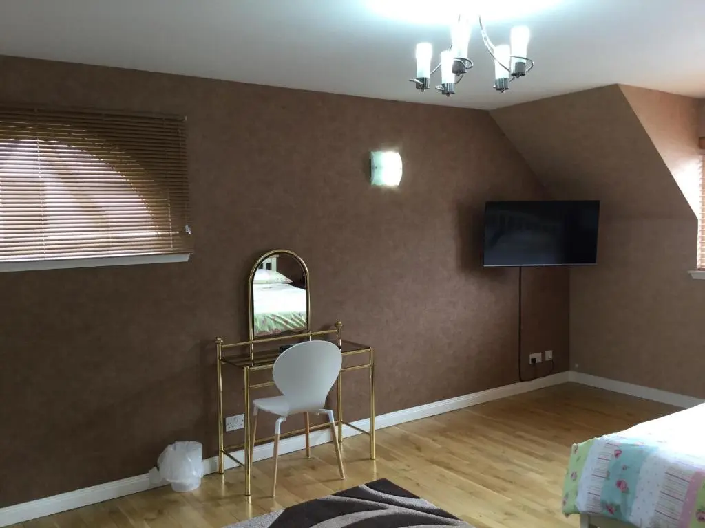 a bedroom with a chair and a tv on the wall at West Heather House Free Parking in Inverness