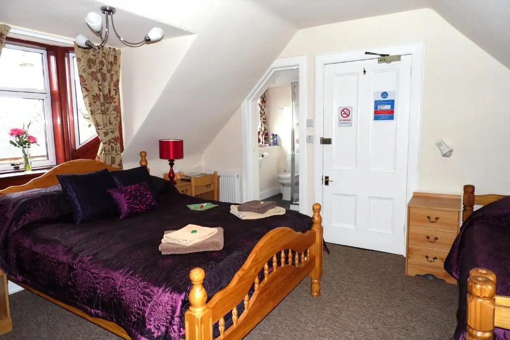 a bedroom with a bed with a purple comforter at Torridon Guest House in Inverness