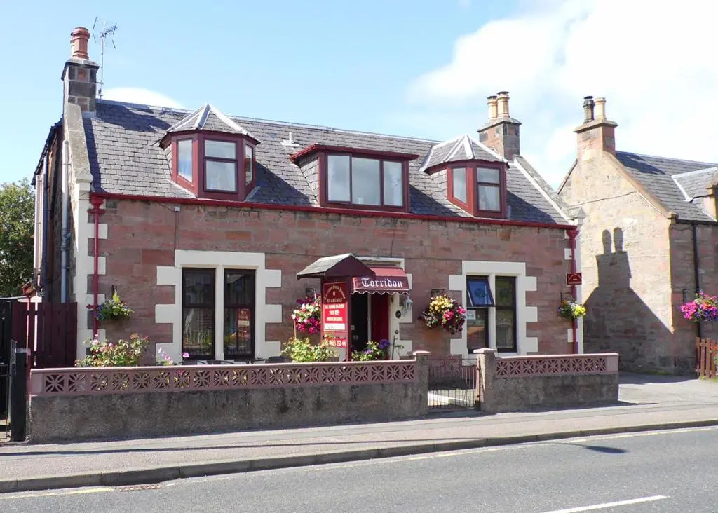 a brick house with a fence in front of it at Torridon Guest House in Inverness