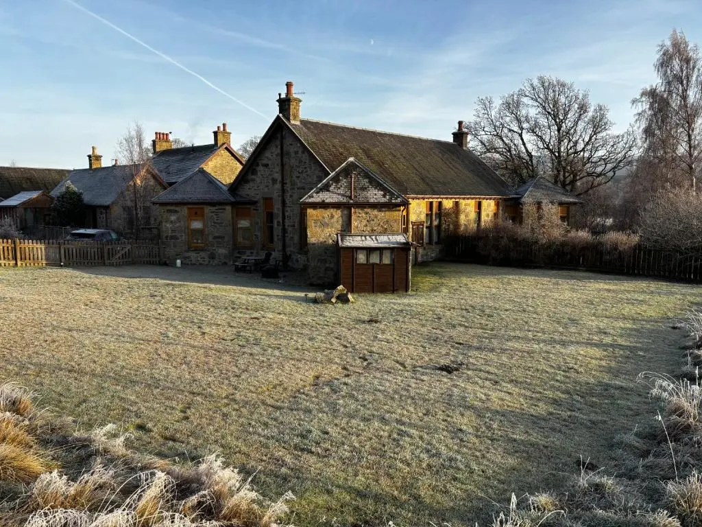 an old house with a large yard in front of it at Shetland Cottage Kincraig in Kincraig