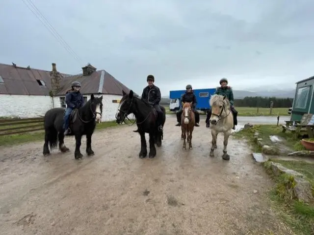 a group of people riding horses on a dirt road at Shetland Cottage Kincraig in Kincraig