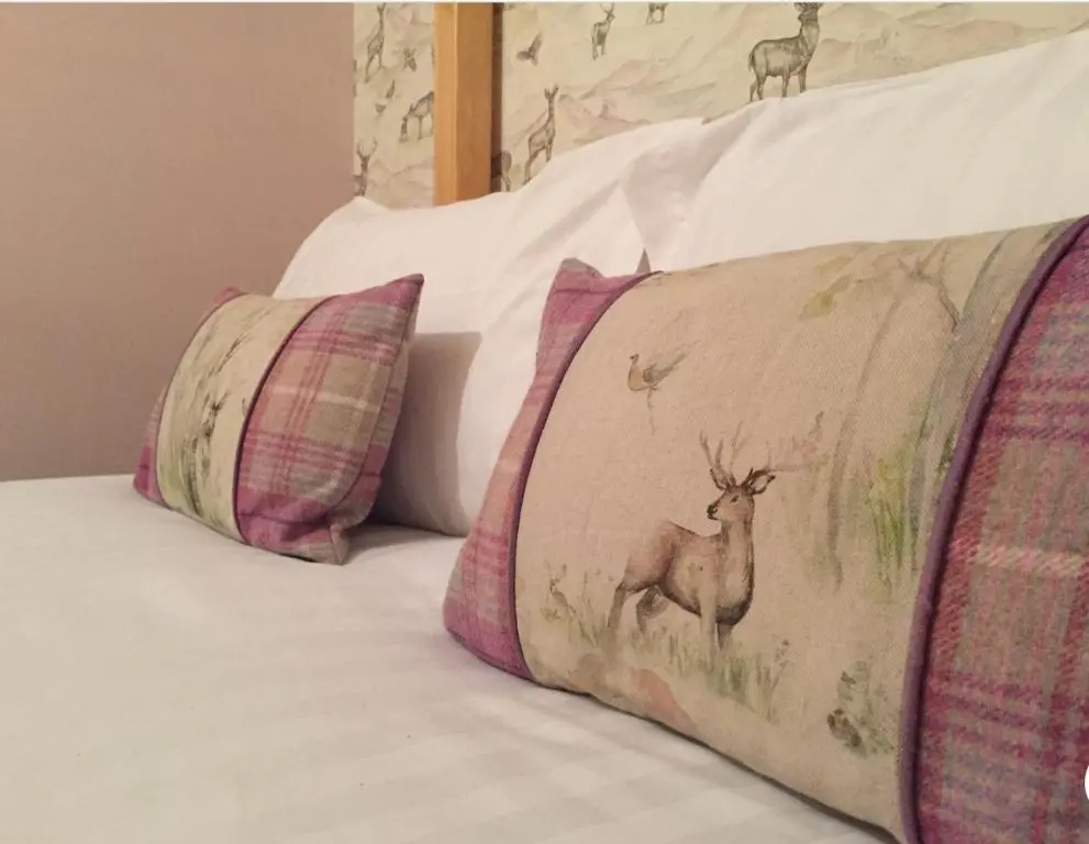 a bed with two pillows and a deer on it at Island View Guest House in Ullapool