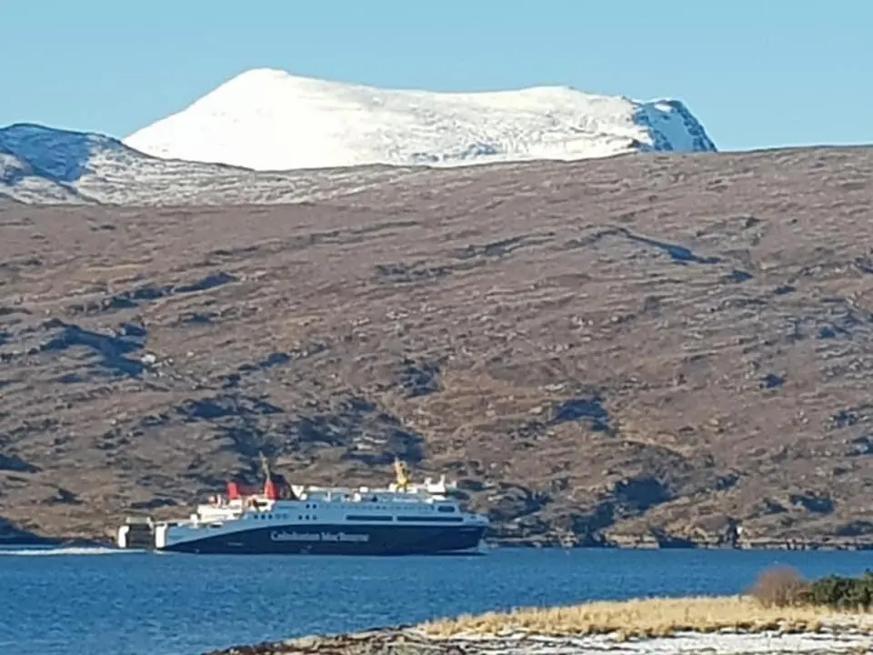 a cruise ship in the water with a snow covered mountain at Island View Guest House in Ullapool
