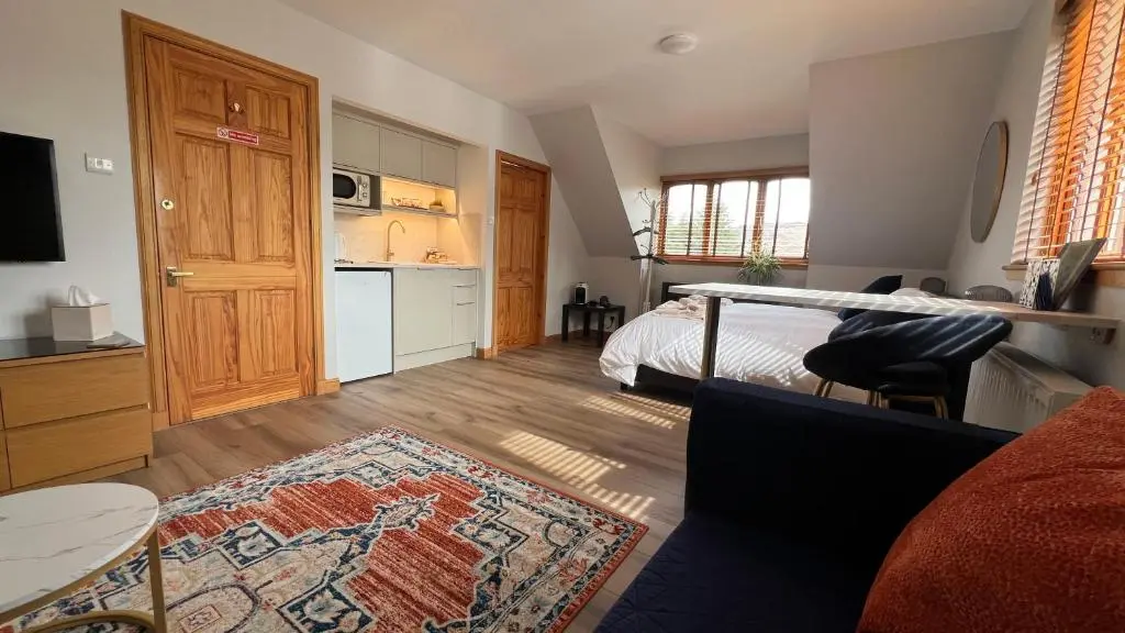 a bedroom with a bed and a kitchen and a living room at Carn A Chuilinn House in Fort Augustus