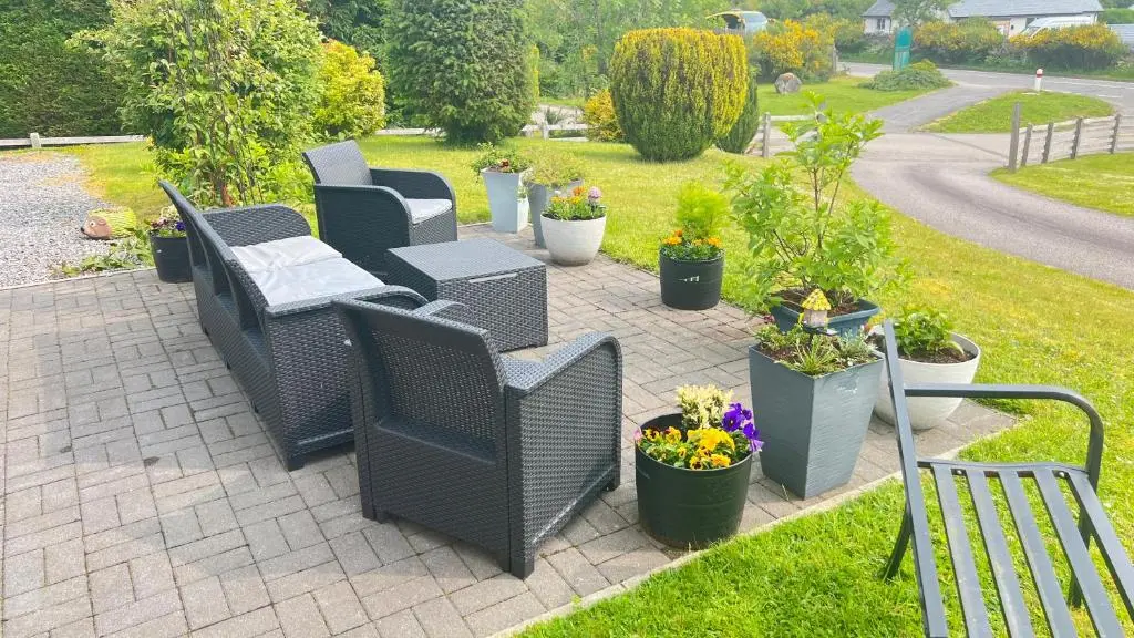 a patio with wicker chairs and potted plants at Carn A Chuilinn House in Fort Augustus