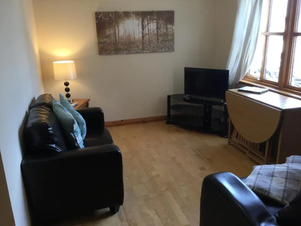 a living room with a couch and a television at Culloden Apartment Free Parking in Inverness