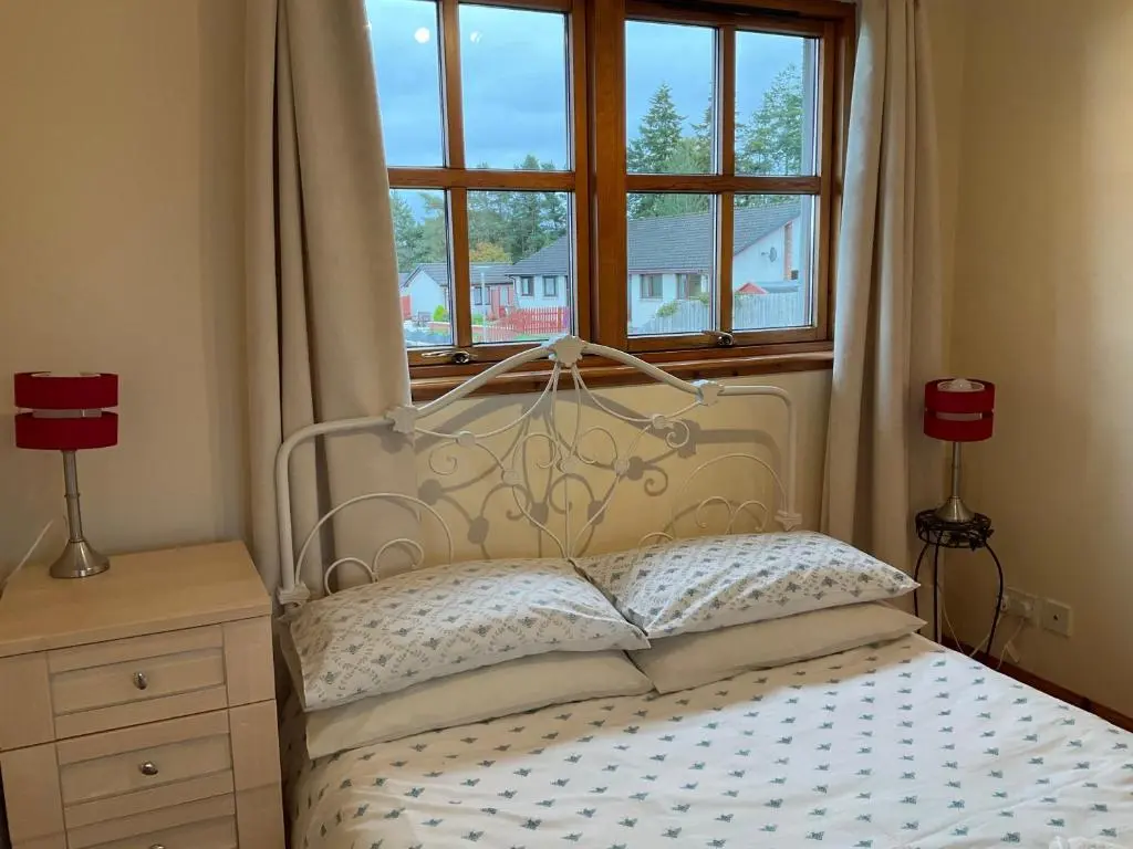 a bedroom with a bed with two lamps and a window at Culloden Apartment Free Parking in Inverness