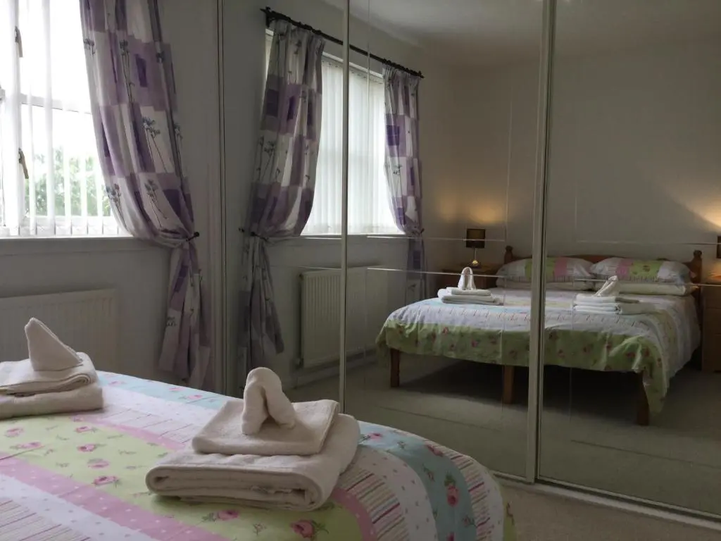 a bedroom with two beds and a mirror at Castle Heather House Free Parking in Inverness