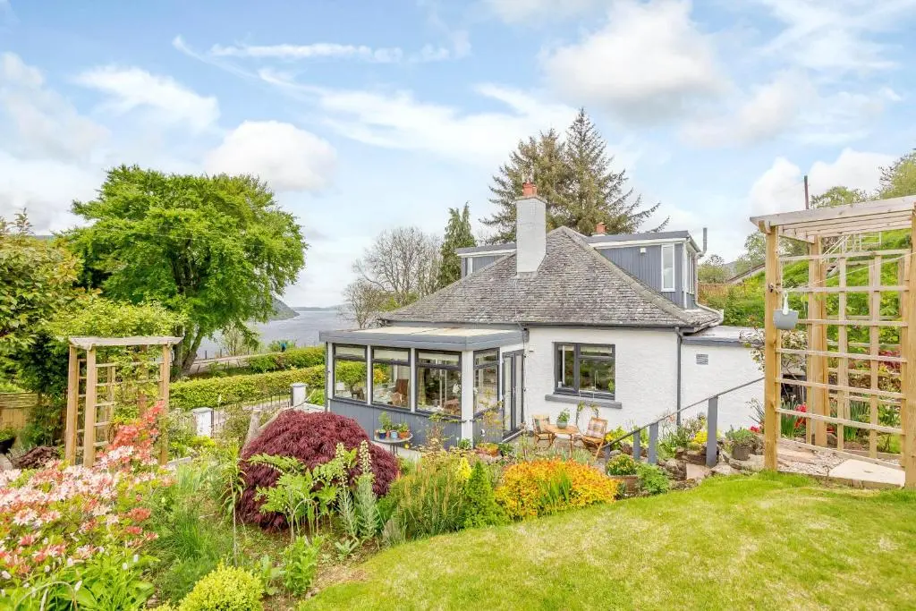 a white house with a garden in front of it at Urquhart Bay B&B in Drumnadrochit