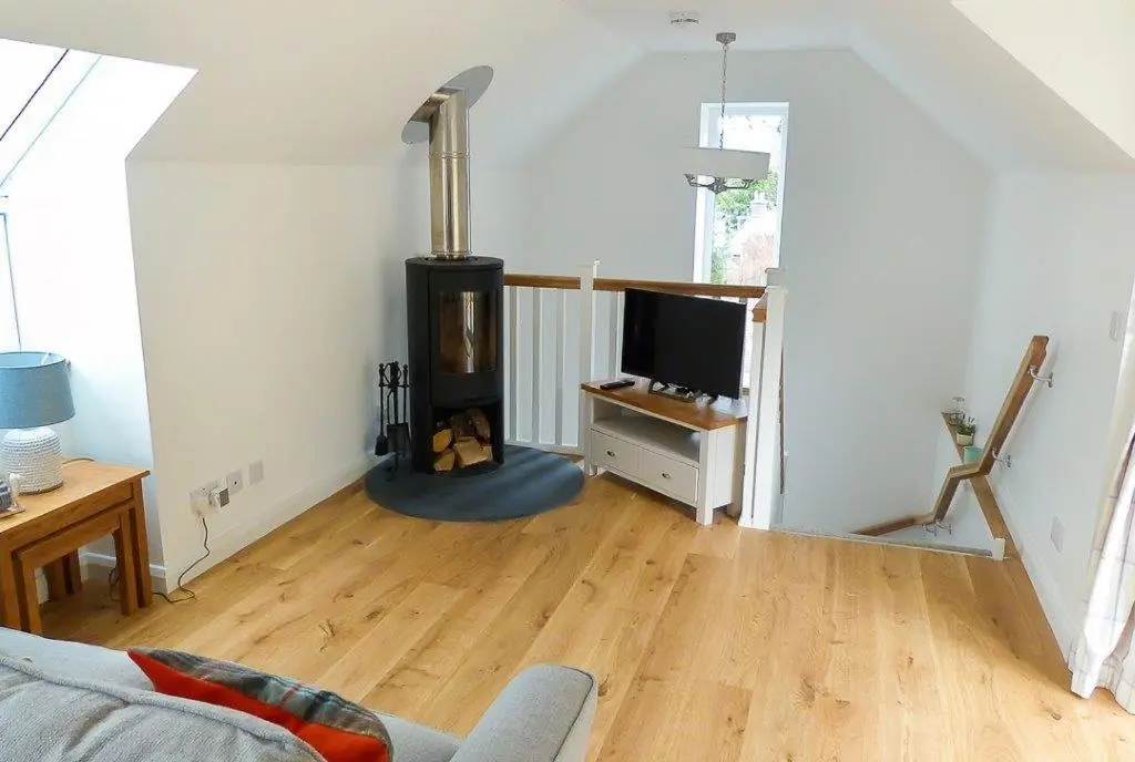 a living room with a wood stove in the corner at Urquhart Bay Croft in Drumnadrochit